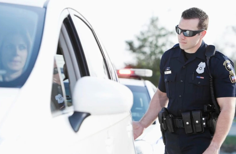 Полицейский в США дотрагивается рукой до машины.